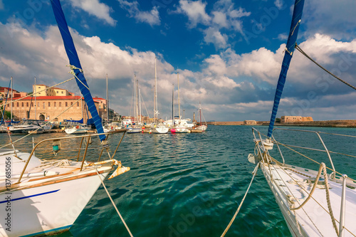 Venetian shipyards, and fishing boats in old harbour of Chania in cloudy summer morning, Crete, Greece photo