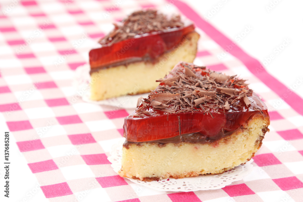 served two slices of delicious cherry cheese cake with cherry topping and decorated with chocolate on checkered tablecloth served two slices of delicious cherry cheese cake with cherry topping and decorated with chocolate on checkered tablecloth