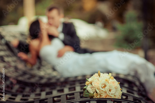 wedding couple hugging, the bride holding a bouquet of flowers in her hand, the groom embracing her photo