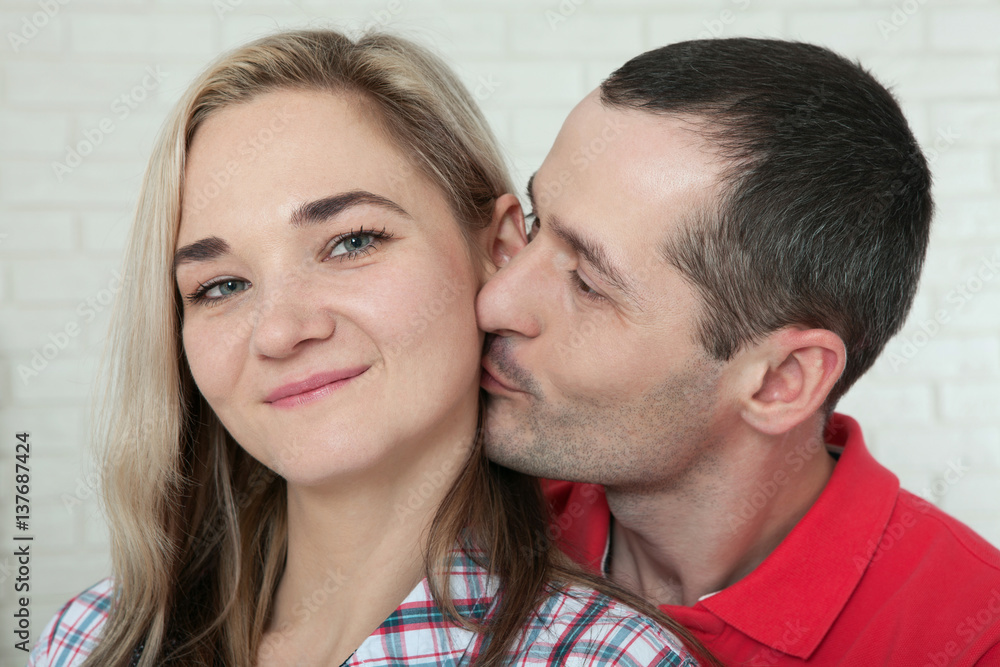 Cheerful young couple at home. Woman and man hugs and kisses at home. Cheerful young couple at home. Woman and man hugs and kisses at home.