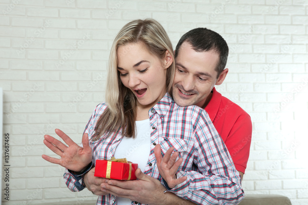 valentine's day or christmas concept - young woman opening gift from her boyfriend valentine's day or christmas concept - young woman opening gift from her boyfriend