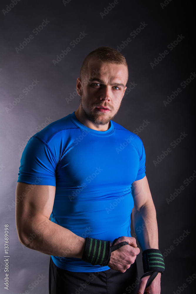 Portrait of a muscular young man standing in studio on black studio background Portrait of a muscular young man standing in studio on black studio background