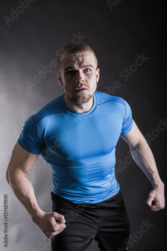 Portrait of a muscular aggressive young man standing in studio on black studio background