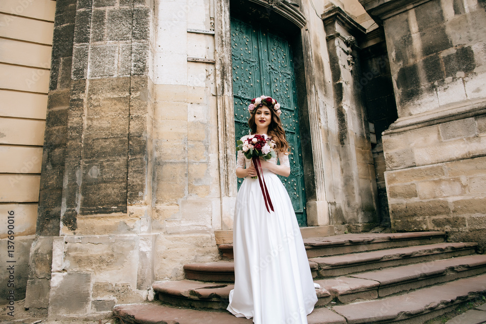  Bride in wreath walking city street  in  wedding dress and with beautiful  bouquet