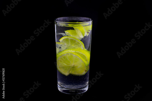slices of lime in glass of water on black background