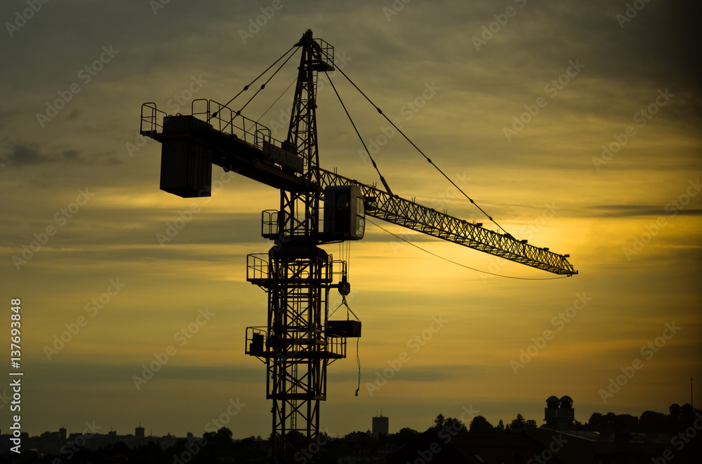 Yellow construction crane against cloudy sky at sunrise in Belgrade, Serbia