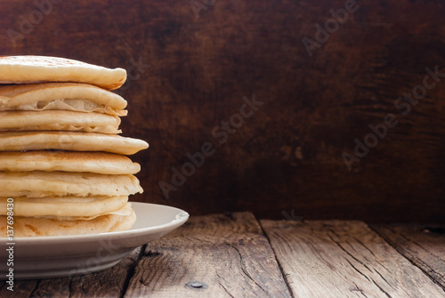 Stack of pancakes with honey on wooden background.