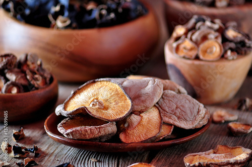 Various organic dried Chinese mushrooms in a wooden bowl on the old wooden background.