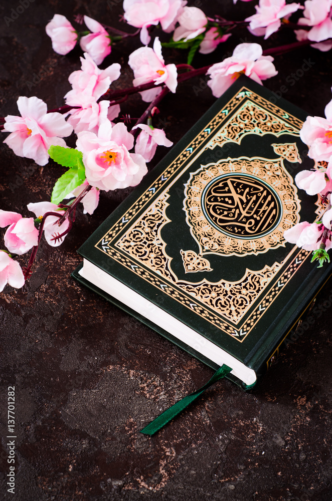 Islamic Book Koran and spring flowers brunch on dark background with