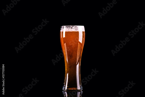 Beer glass with foam on black background