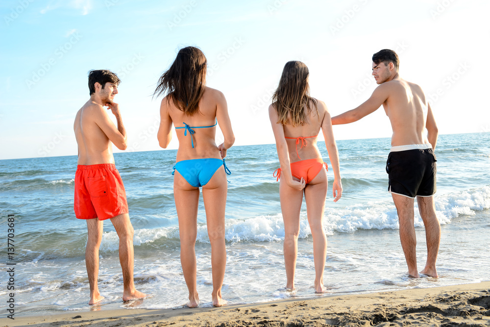 four happy friends young people man and woman having fun at ocean beach jumping together in the sea four happy friends young people man and woman having fun at ocean beach jumping together in the sea