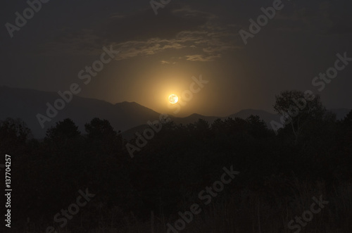 Enchanting nocturnal rural scene with full moon rising over the the mountains and forest. Big Caucasus. Azerbaijan. Sheki