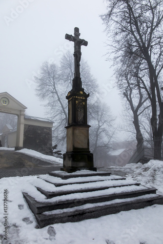 Old cross in front of the entrance to the International Shrine of St. Anna, the winter fog. Mount St. Anna,