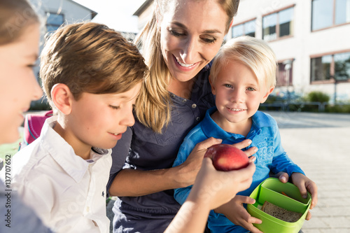 Mutter und Kinder in Schule machen Pause mit Apfel und Brotdose