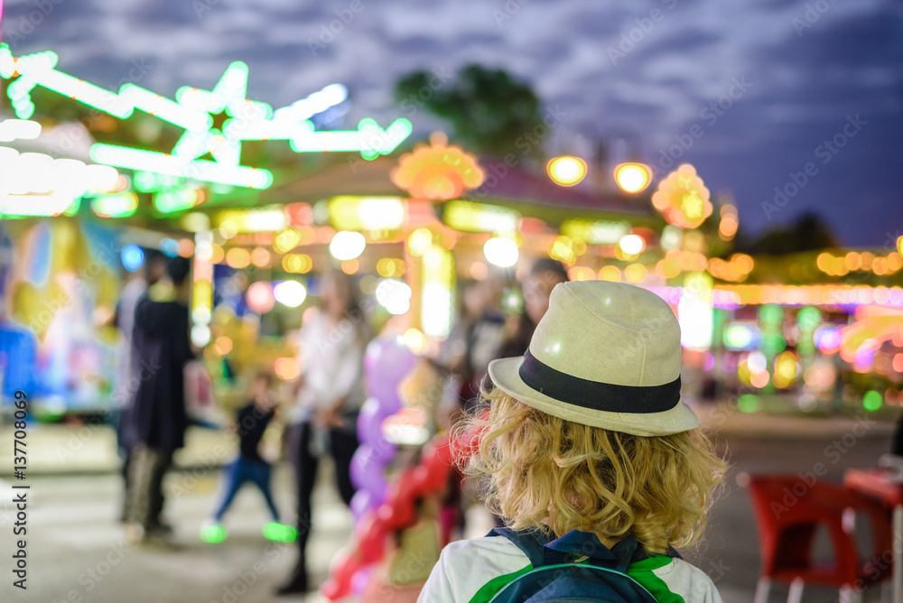 Back view of joyful cute child boy on night bokeh amuzement park outdoors background Back view of joyful cute child boy on night bokeh amuzement park outdoors background