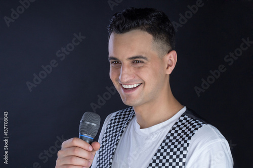 Male black-haired singer performs singing to microphone photo