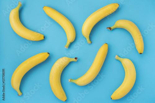 Summer pattern with bananas on blue background. Minimal styled flat lay.