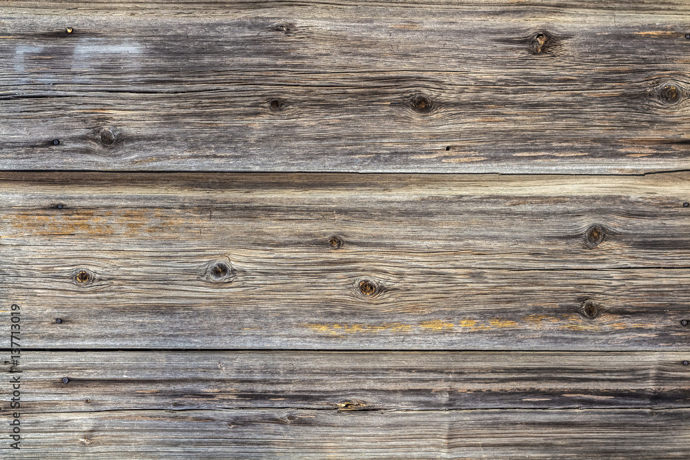 The wall surface of old weathered unpainted boards. Background The wall surface of old weathered unpainted boards. Background