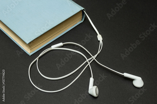 Blue book with headphones on a black background