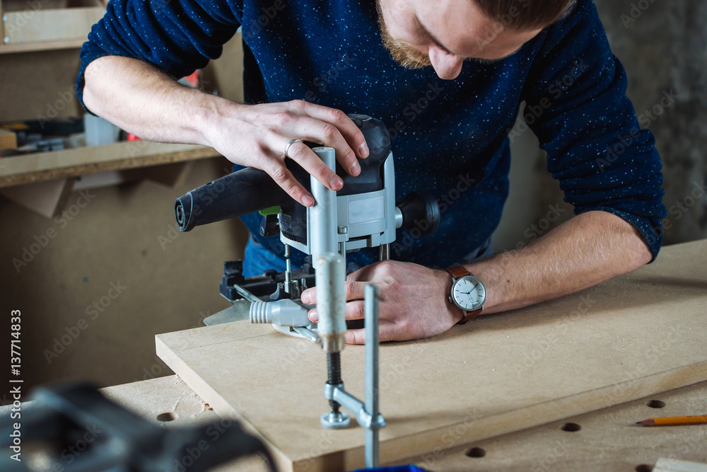 Young man working as carpenter and cutting board Young man working as carpenter and cutting board