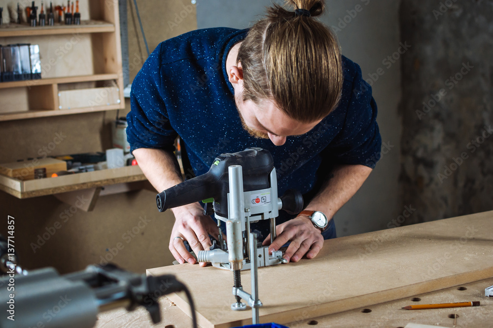 Young man working as carpenter and cutting board Young man working as carpenter and cutting board