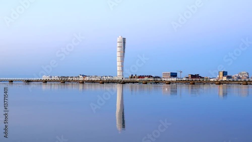 Turning Torso skyscraper building reflected in calm water surface. Modern architecture apartment tower block by the sea