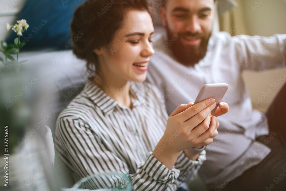 Young adults male and female with smartphone having fun home Young adults male and female with smartphone having fun home