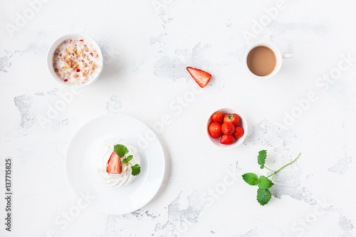 Breakfast with cup of coffee, muesli, sweet dessert, strawberry. Flat lay, top view