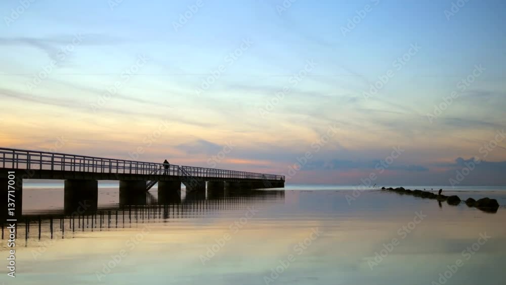 Pier and stones at twilight. Tranquil sea water reflections Pier and stones at twilight. Tranquil sea water reflections