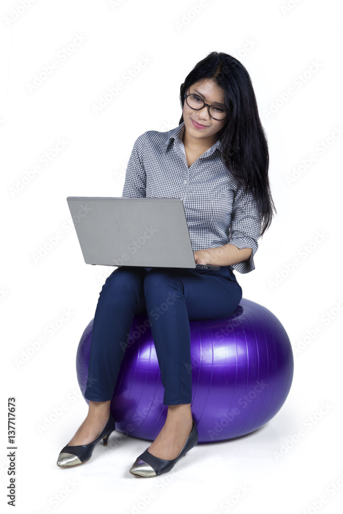 Female entrepreneur sits on ball with laptop Female entrepreneur sits on ball with laptop