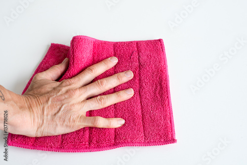 Close up high angle view of woman's hand holding pink microfibre cleaning cloth (selective focus)