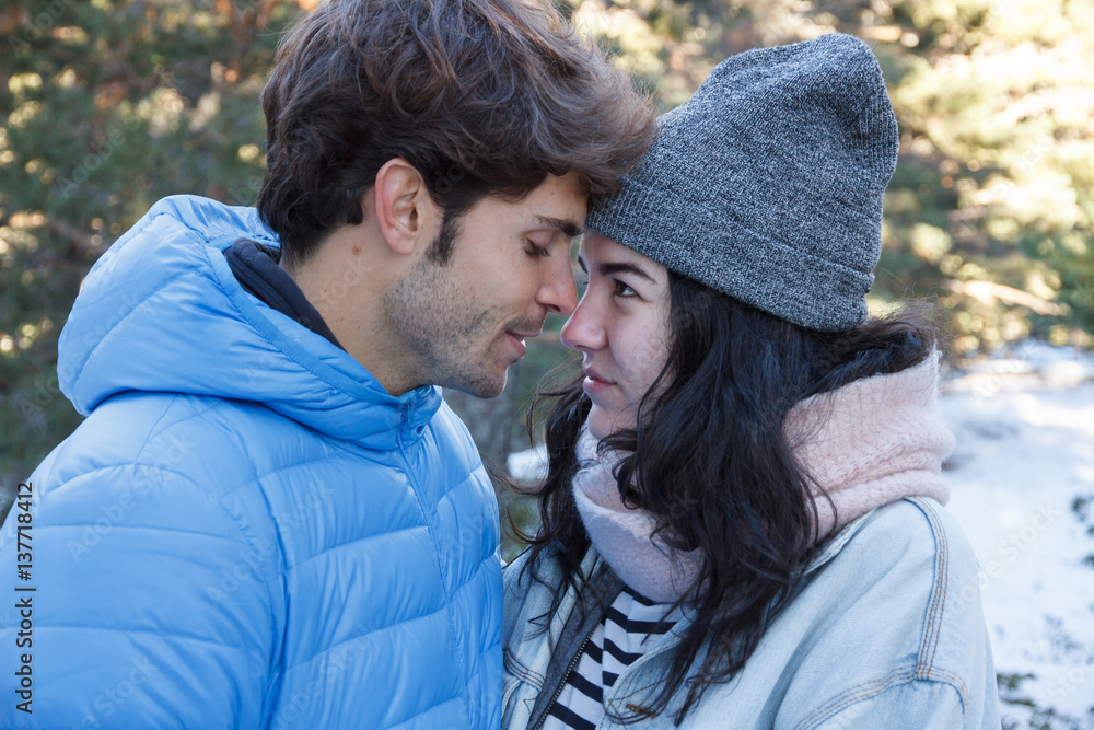 Young couple, boyfriend and girlfriend kissing and hugging in the mountains on a snowy day. They are on a date traveling to the snowy forest. Young couple, boyfriend and girlfriend kissing and hugging in the mountains on a snowy day. They are on a date traveling to the snowy forest.