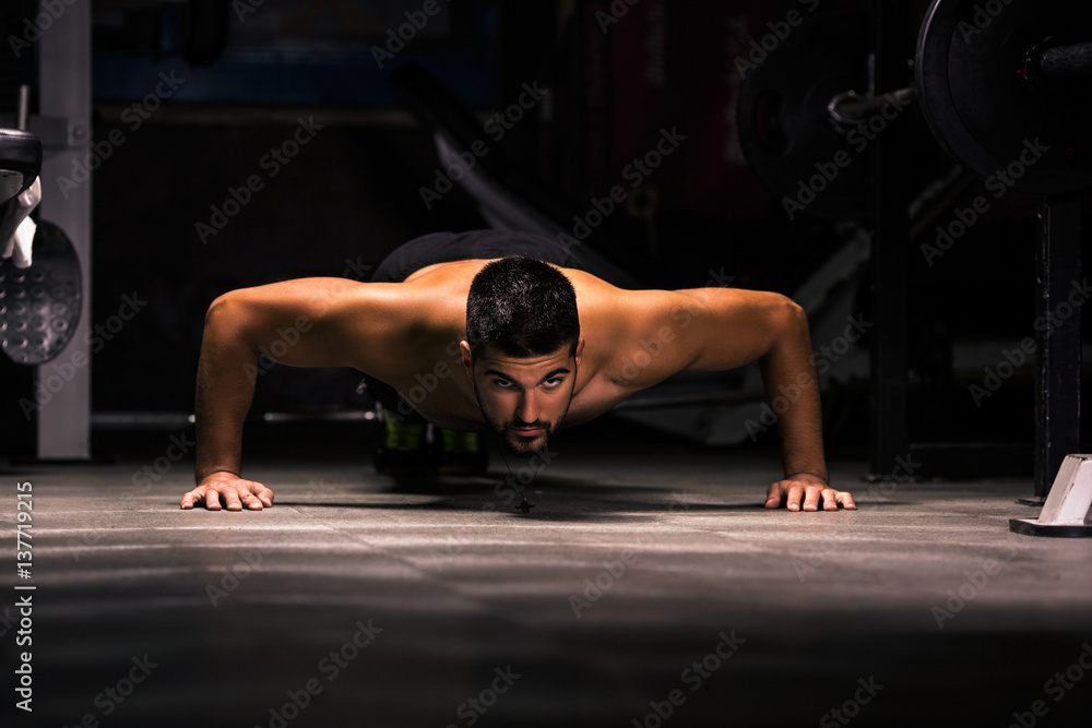 Fototapeta premium Young man is exercising in the gym doing push-ups.