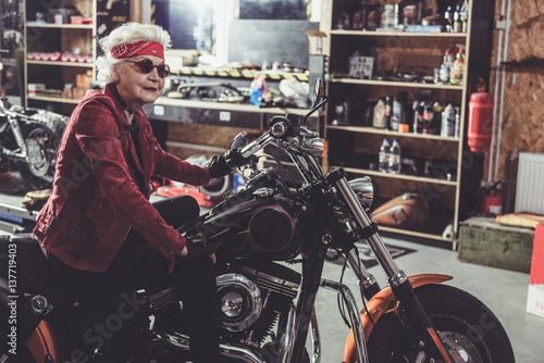 Cheerful pensioner locating on bike in garage