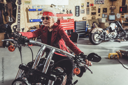 Smiling driving on motorcycle in mechanic shop