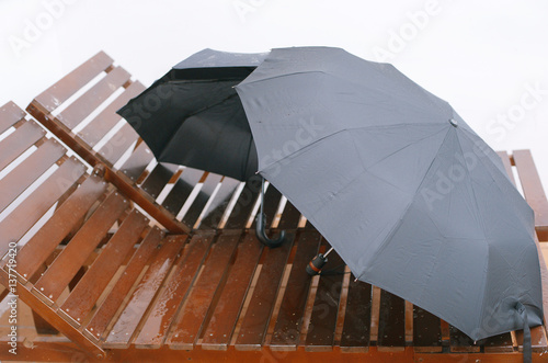 two black umbrella on wooden brown couches on a white background