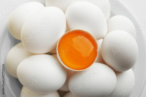 Raw eggs and yolk on plate, closeup
