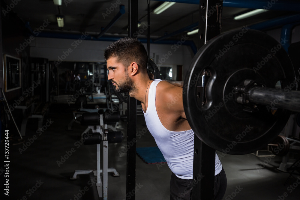 Muscular young man is working out in gym Muscular young man is working out in gym
