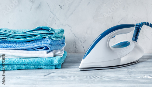 housekeeping set with towels and iron on laundry background photo