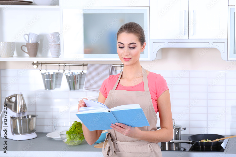 Young woman with cookbook at kitchen Young woman with cookbook at kitchen