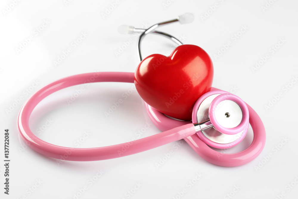 Stethoscope and red plastic heart isolated on white. Cardiology concept Stethoscope and red plastic heart isolated on white. Cardiology concept