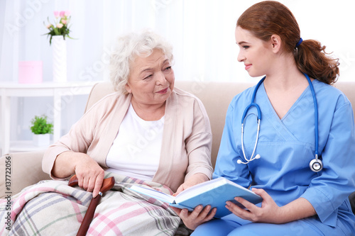 Nurse reading book to elder...