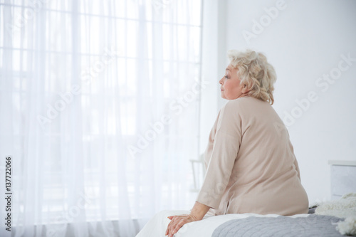 Woman sitting on bed in lig...