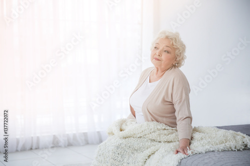 Woman sitting on bed in lig...