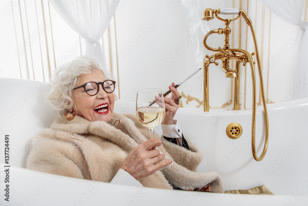 Joyful mature lady relaxing in bathtub Photos | Adobe Stock