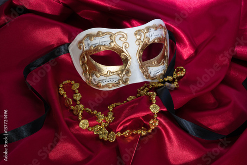 Obraz na plátne Gold and White Mask on Red Satin with Gold Mardi Gras Necklace