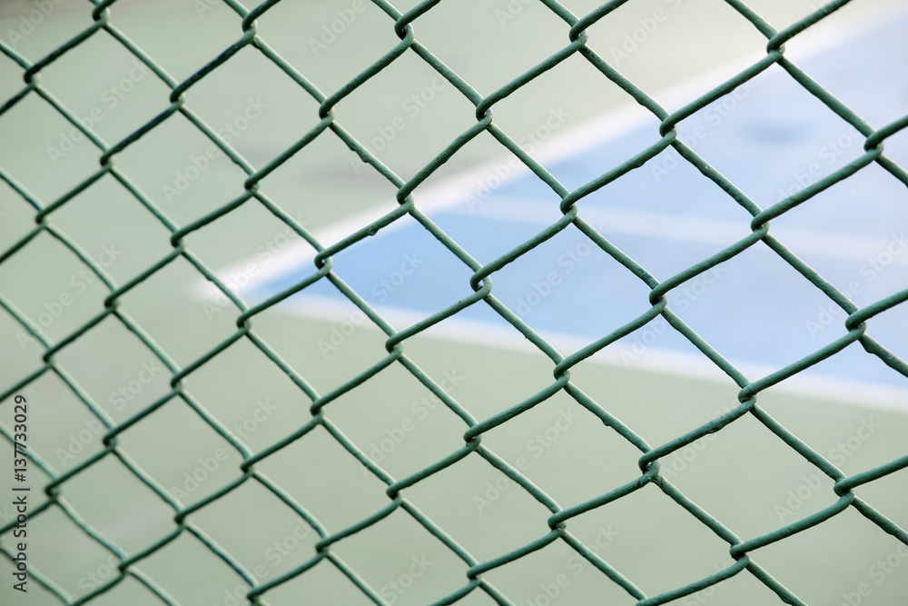 Closeup view of a fence with a blurred tennis court background. Closeup view of a fence with a blurred tennis court background.