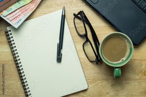 Notebook or note pad smart phone cup of coffee and glasses on Brown wooden background top view with copy space. office desk concept