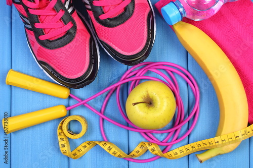 Pair of pink sport shoes, fresh fruits and accessories for fitness on blue boards