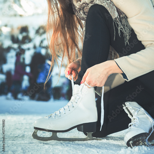 Woman tie shoelaces figure skates at ice rink close-up